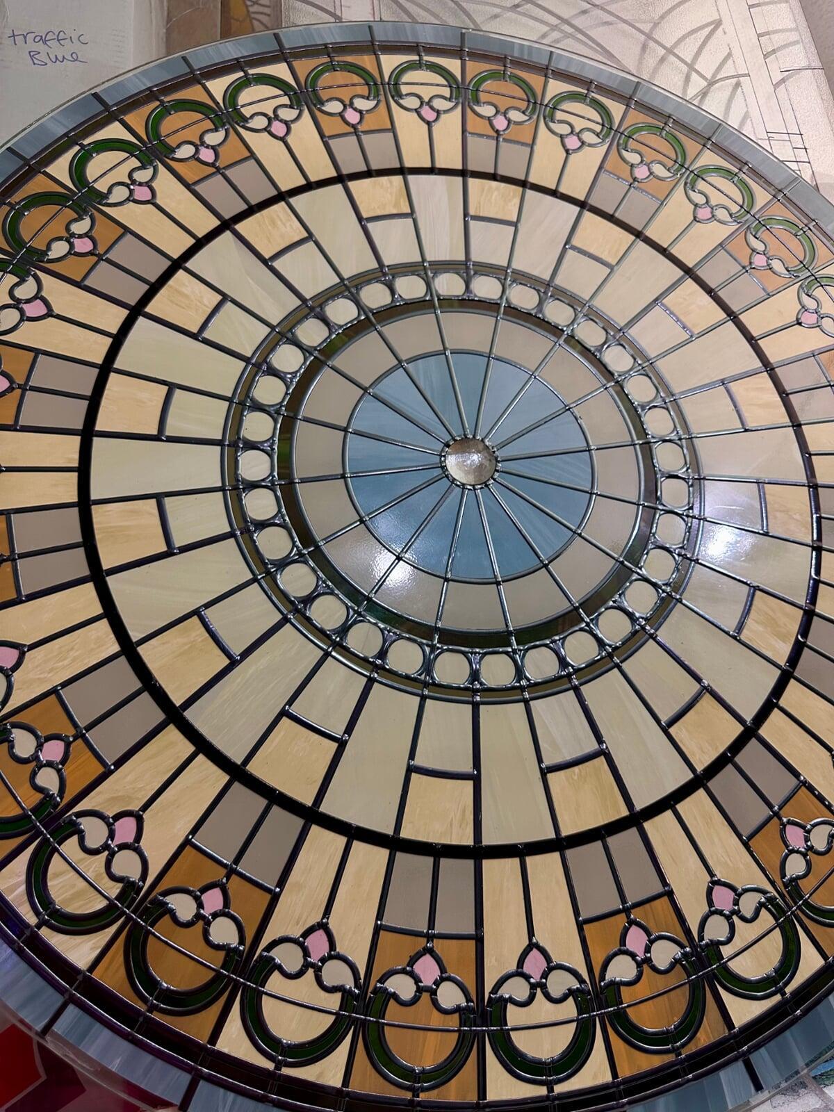 Detailed view of a handcrafted stained glass skylight medallion featuring intricate leadwork and amber glass textures.